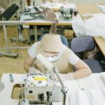 Women expertly sewing in a factory setting, focused on garment production using industrial machines.